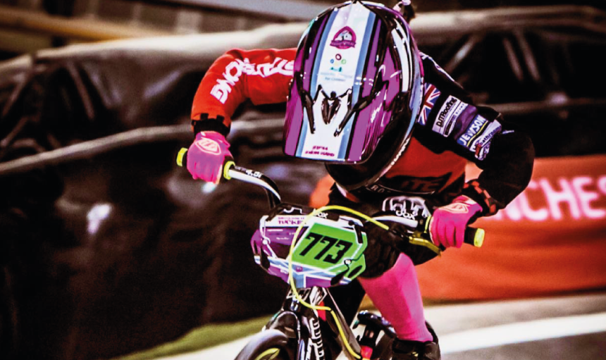 A person racing a BMX bike on an indoor track