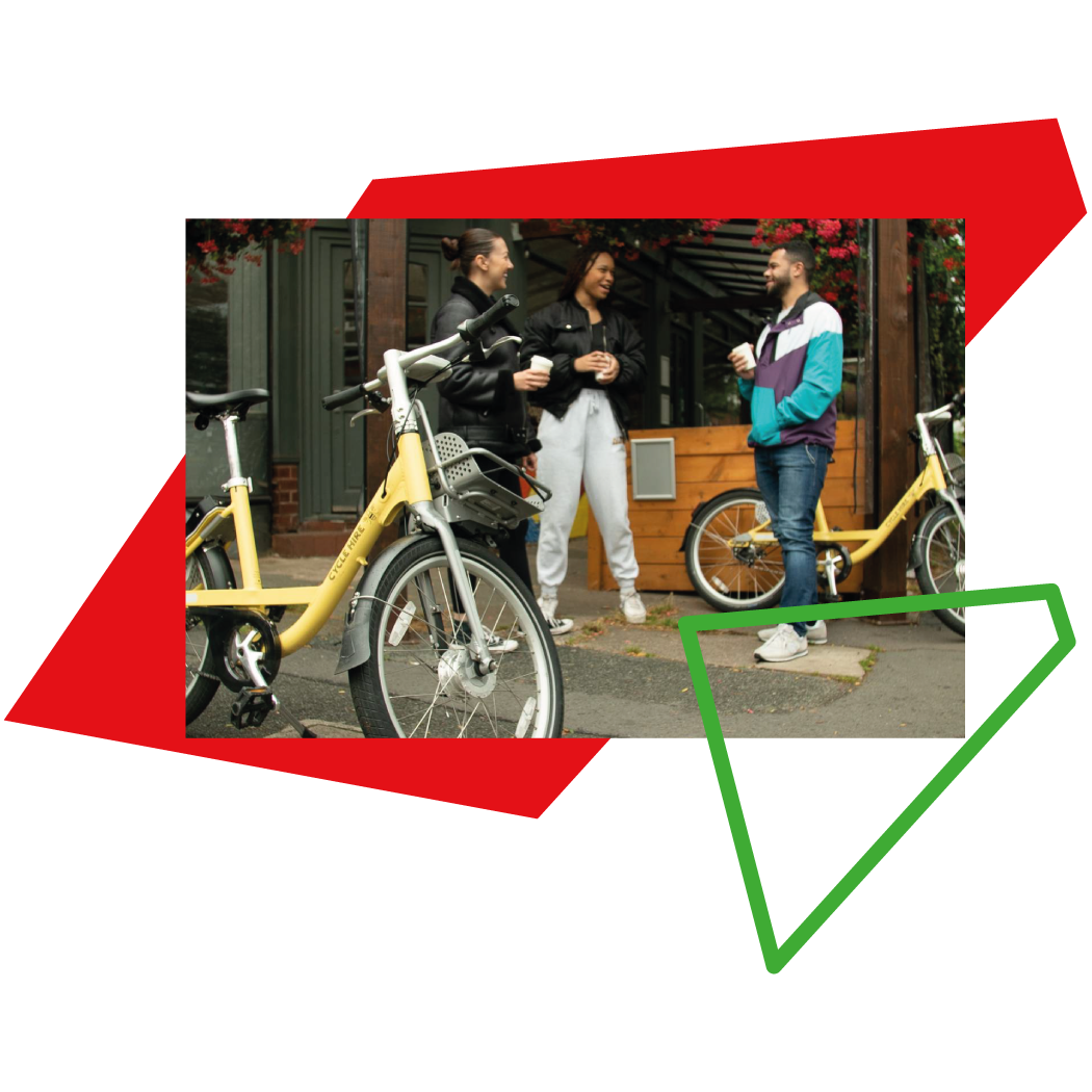 Group of people chatting outside a cafe with cycle hire bikes in the foreground