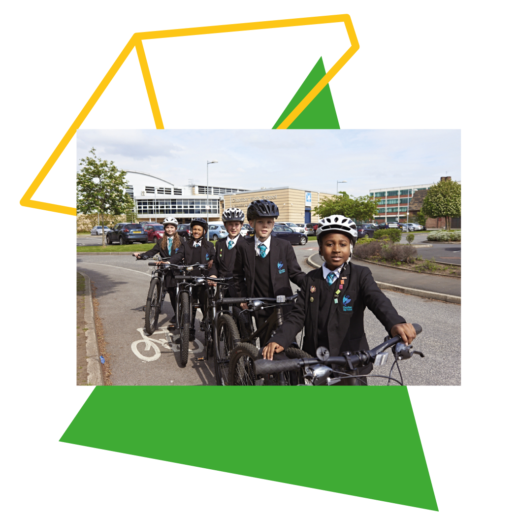 A line of school children standing with bikes in front of a school building